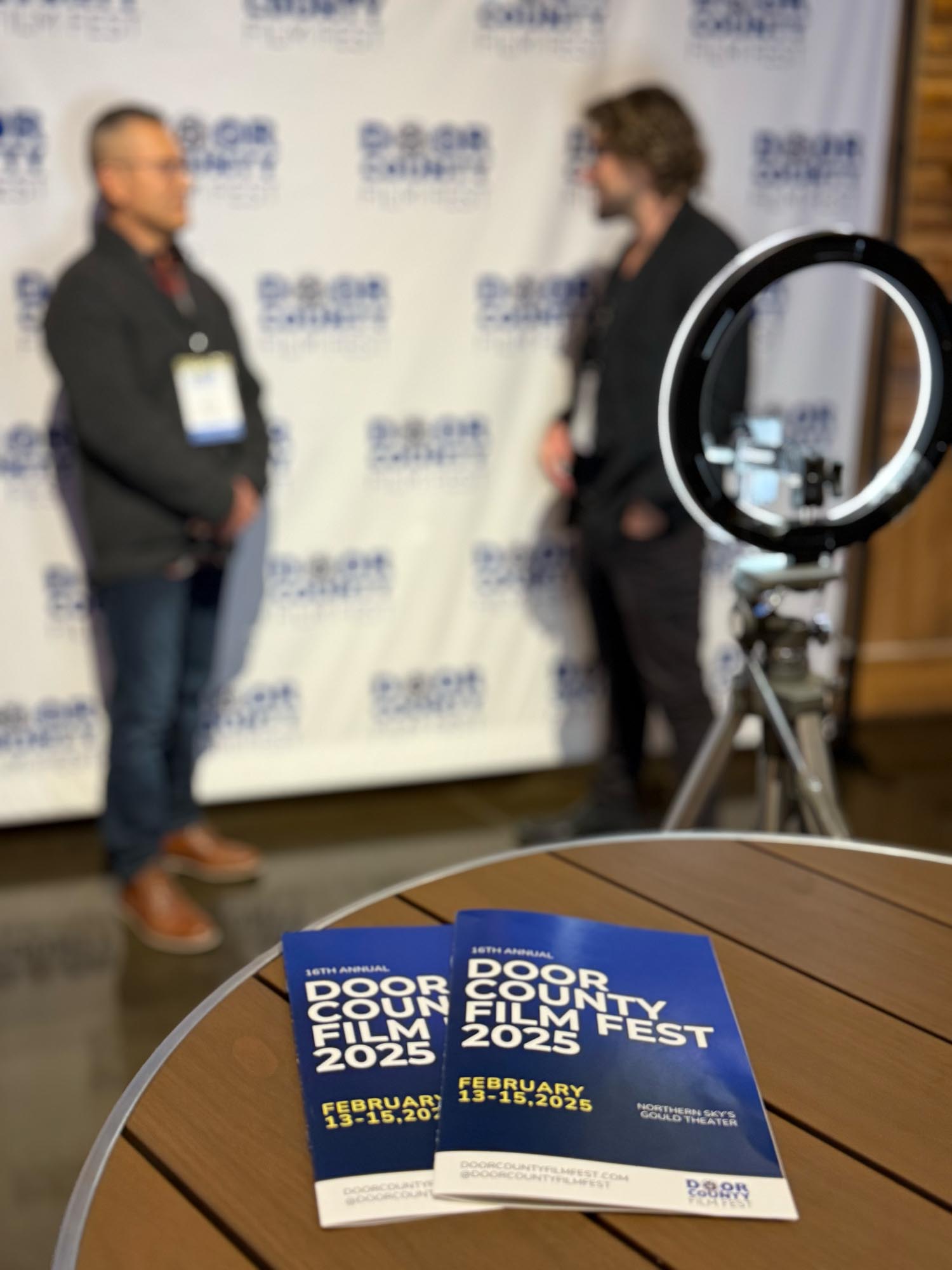 Two of people in front of the the door county film fest with two brochures in the foreground