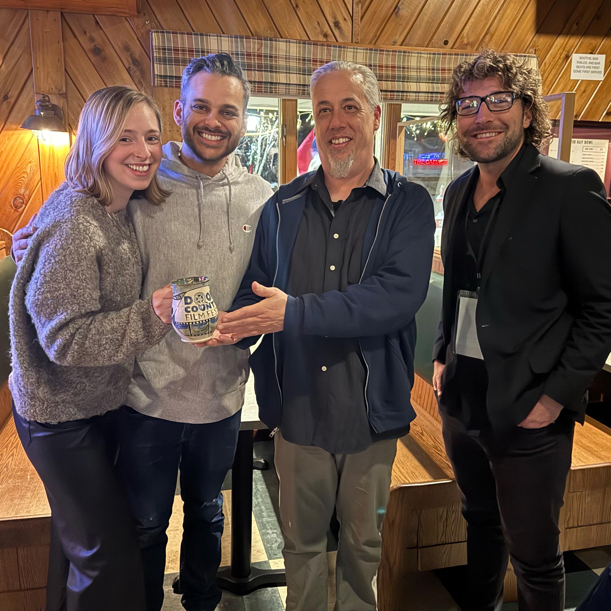 Four people posing for a picture with one of the Door County Film Fest Mugs