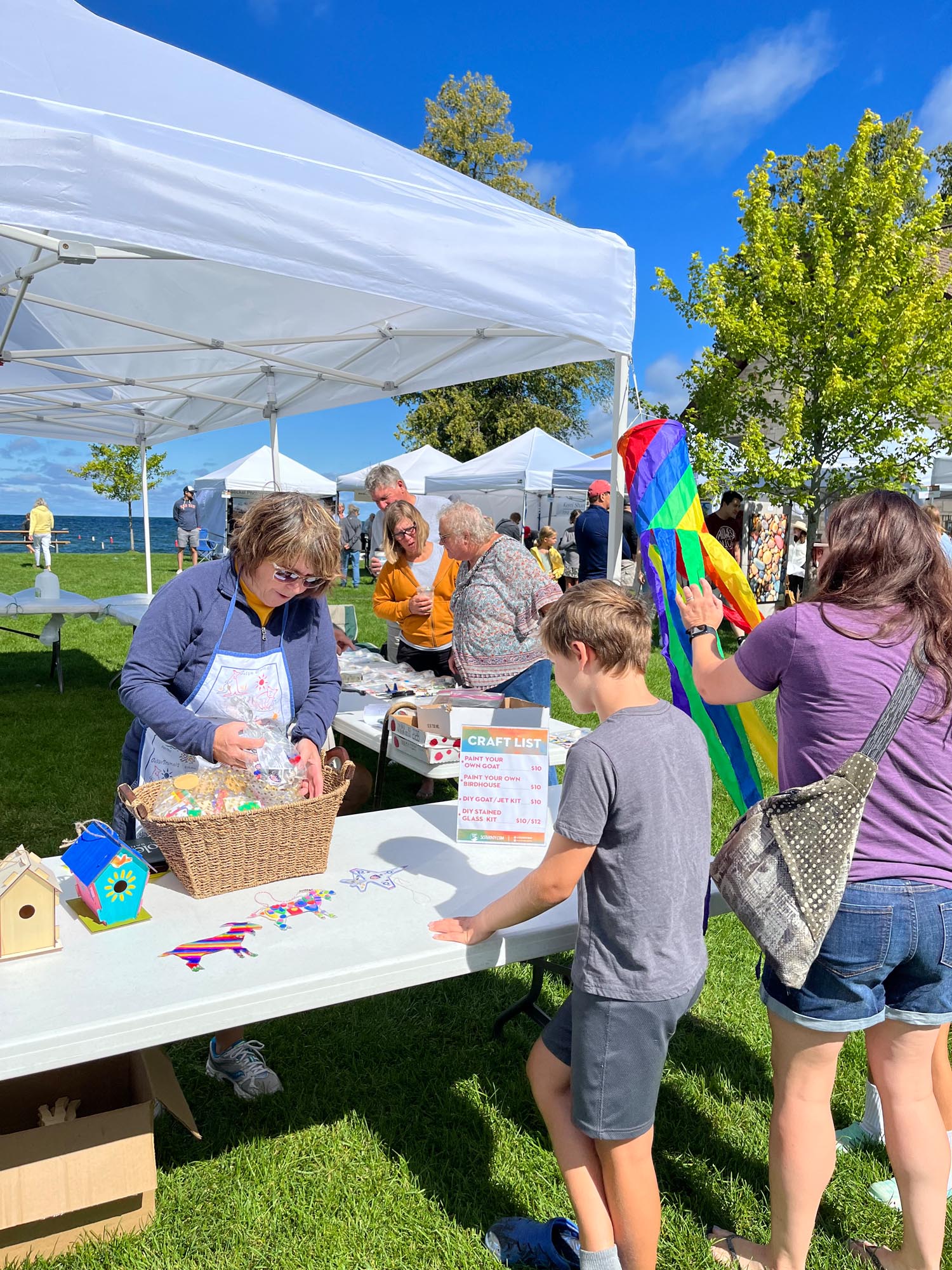 A women digging through a basket of craft for a boy at the Fine Art Fair in Sister Bay