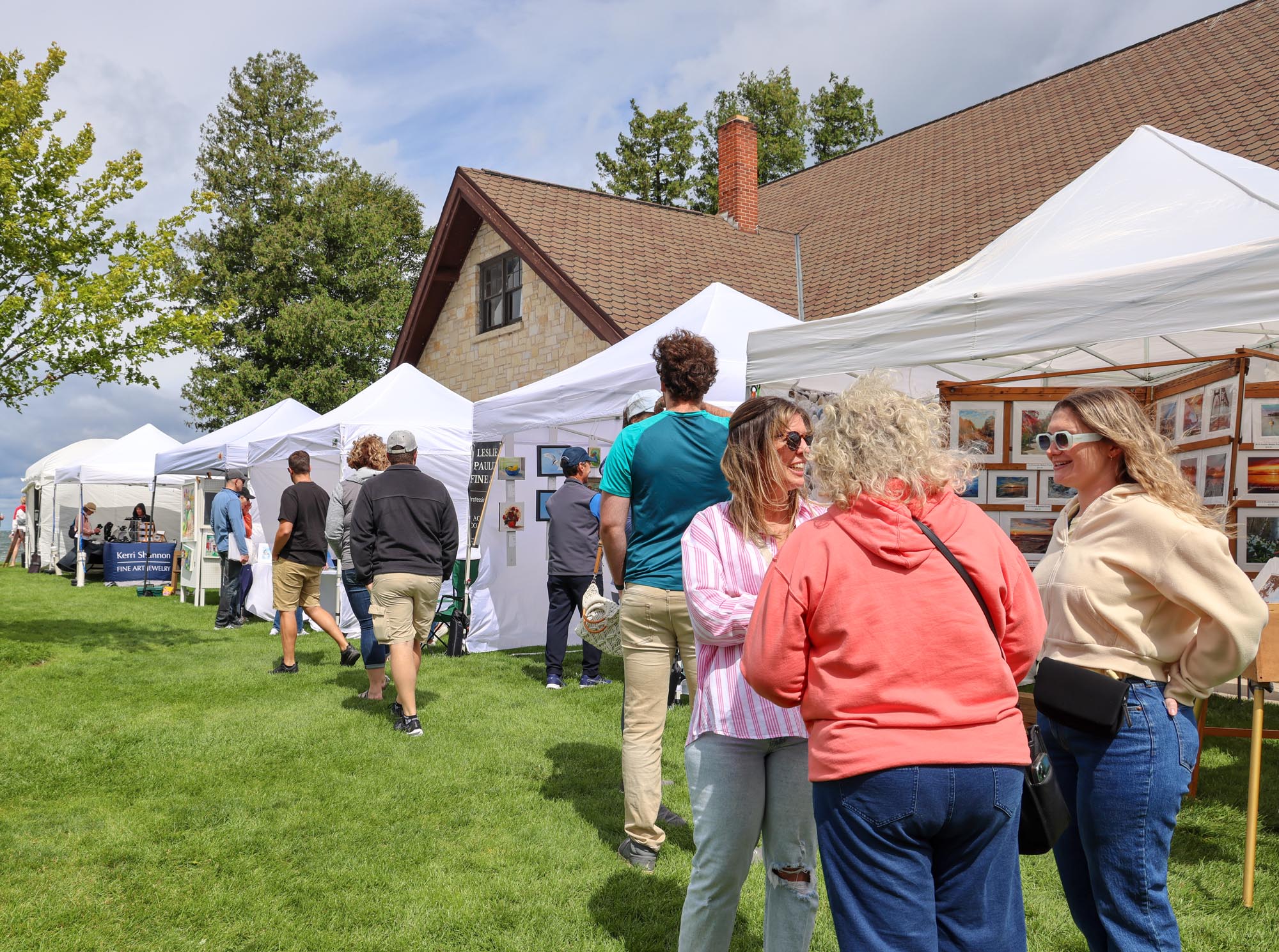 Groups of people hangin out and checking out some tents at the Fine Art Fiar in Sister Bay