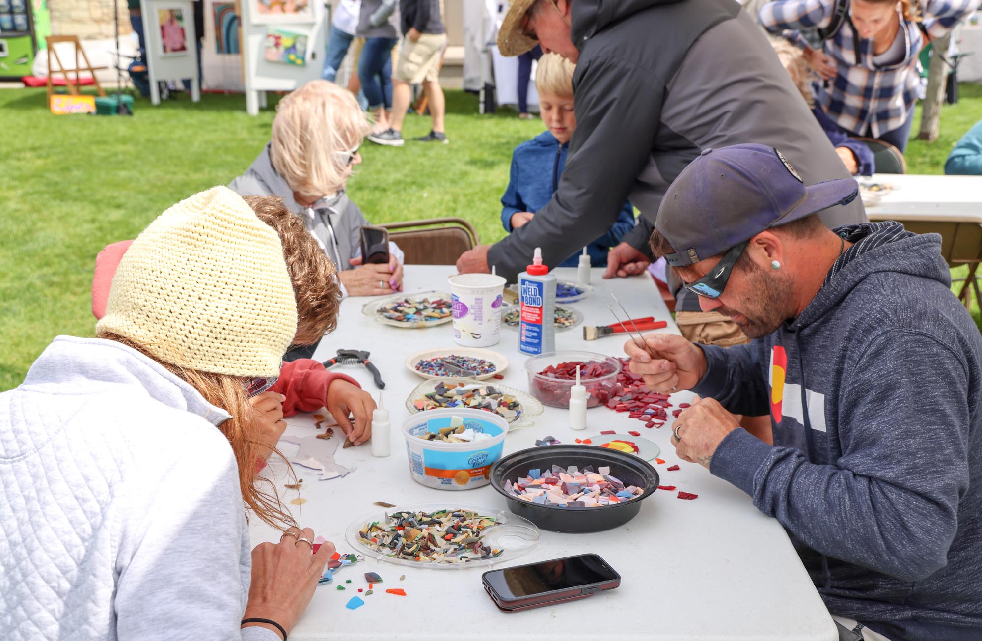 Adults at a table creating goats from chunks of glass.