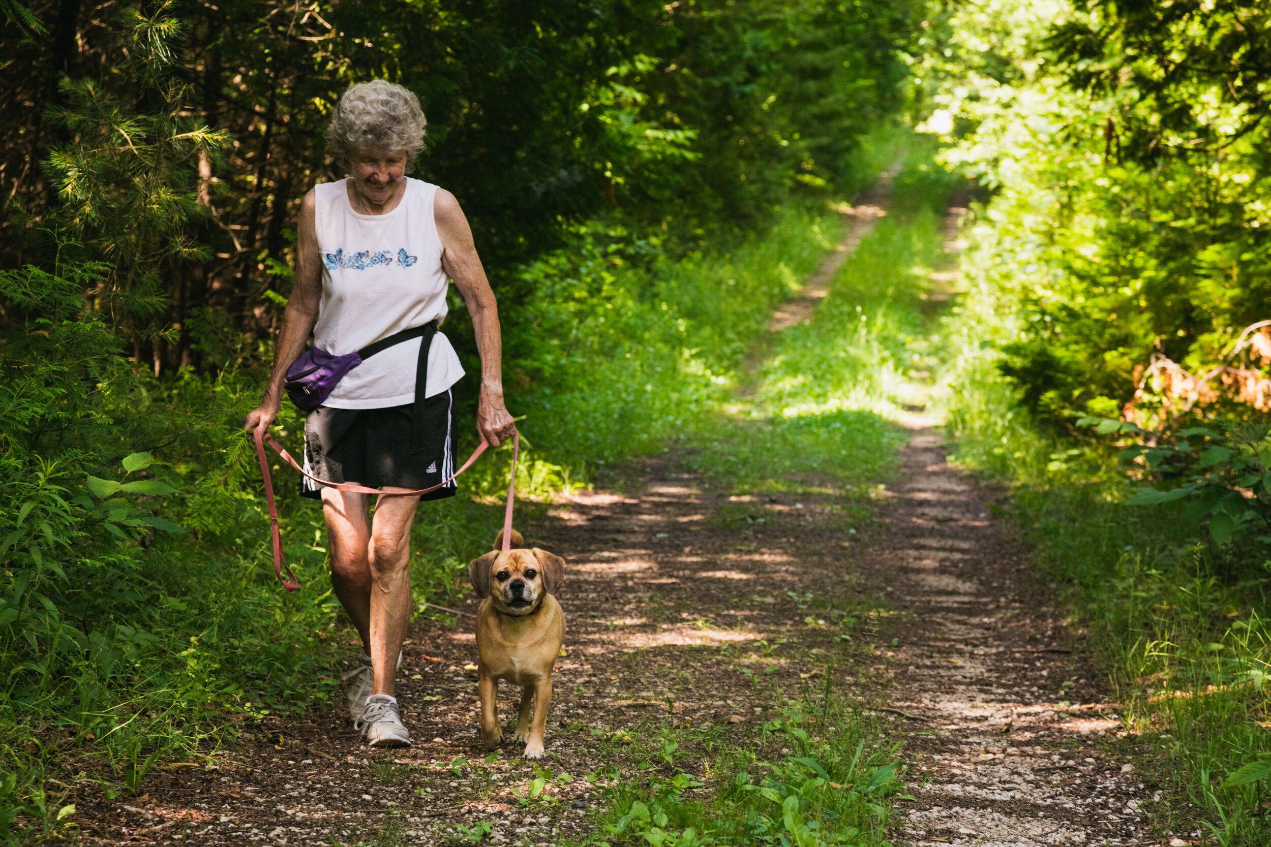 woman walking dog on nature path