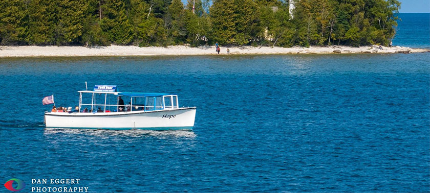 people on a boat going past a lighthouse