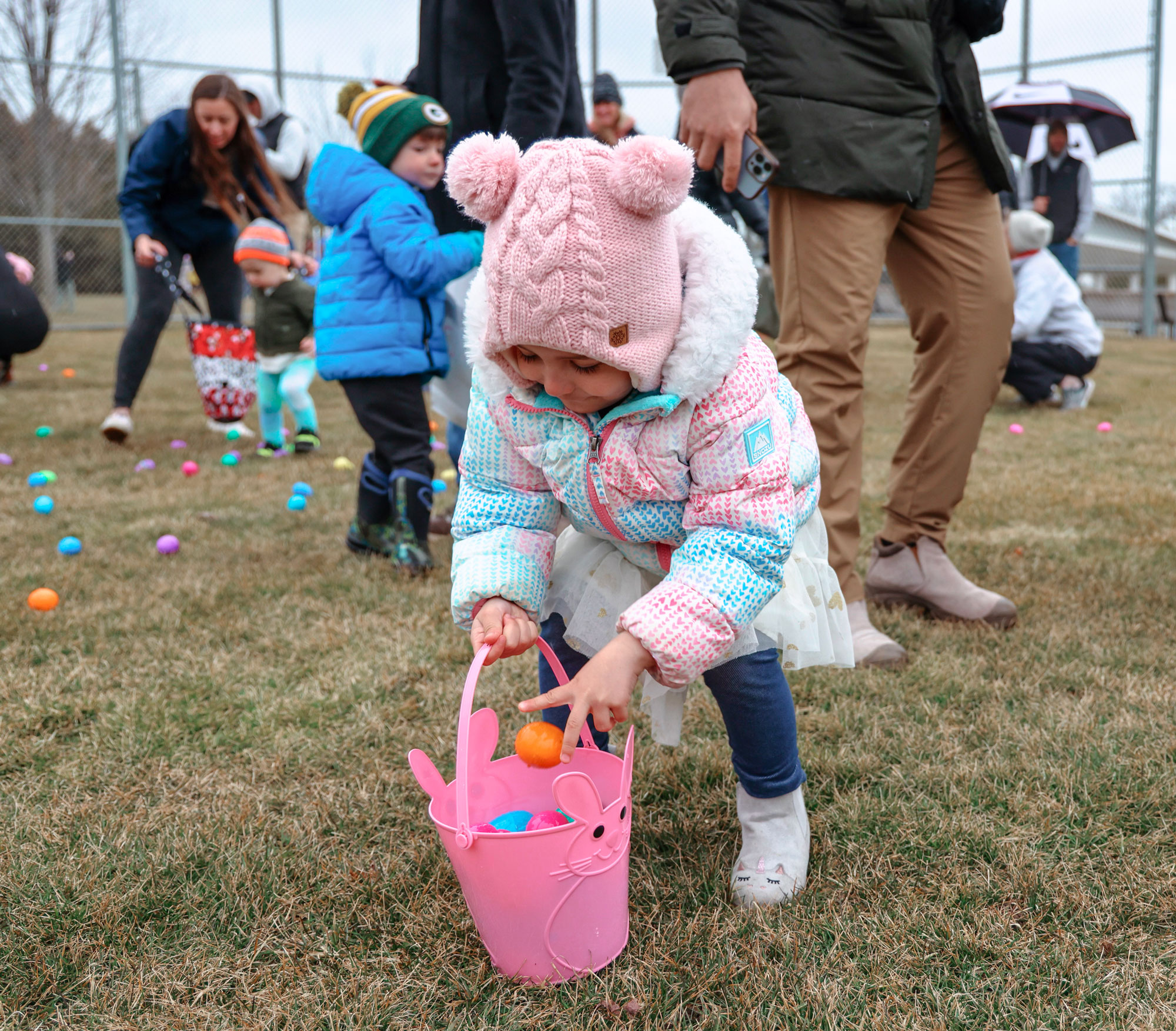 A litter girl picking up an egg in a Easter Egg hunt in Sister Bay