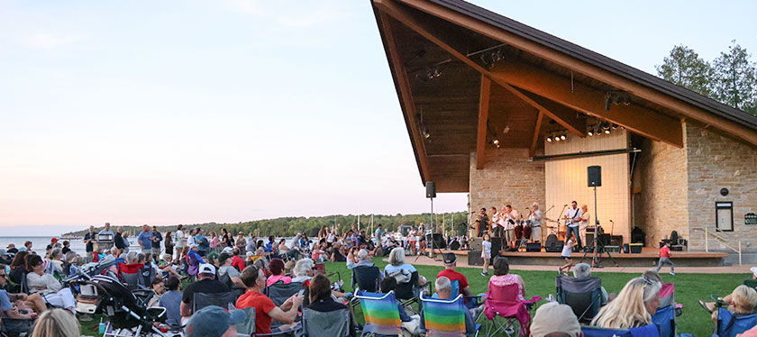 People watching a band perform in the park.