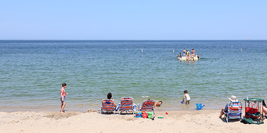SisterBay-Website-Seasonal-Summer1-850x425_041025 Family sitting on beach on warm summer day in Sister Bay