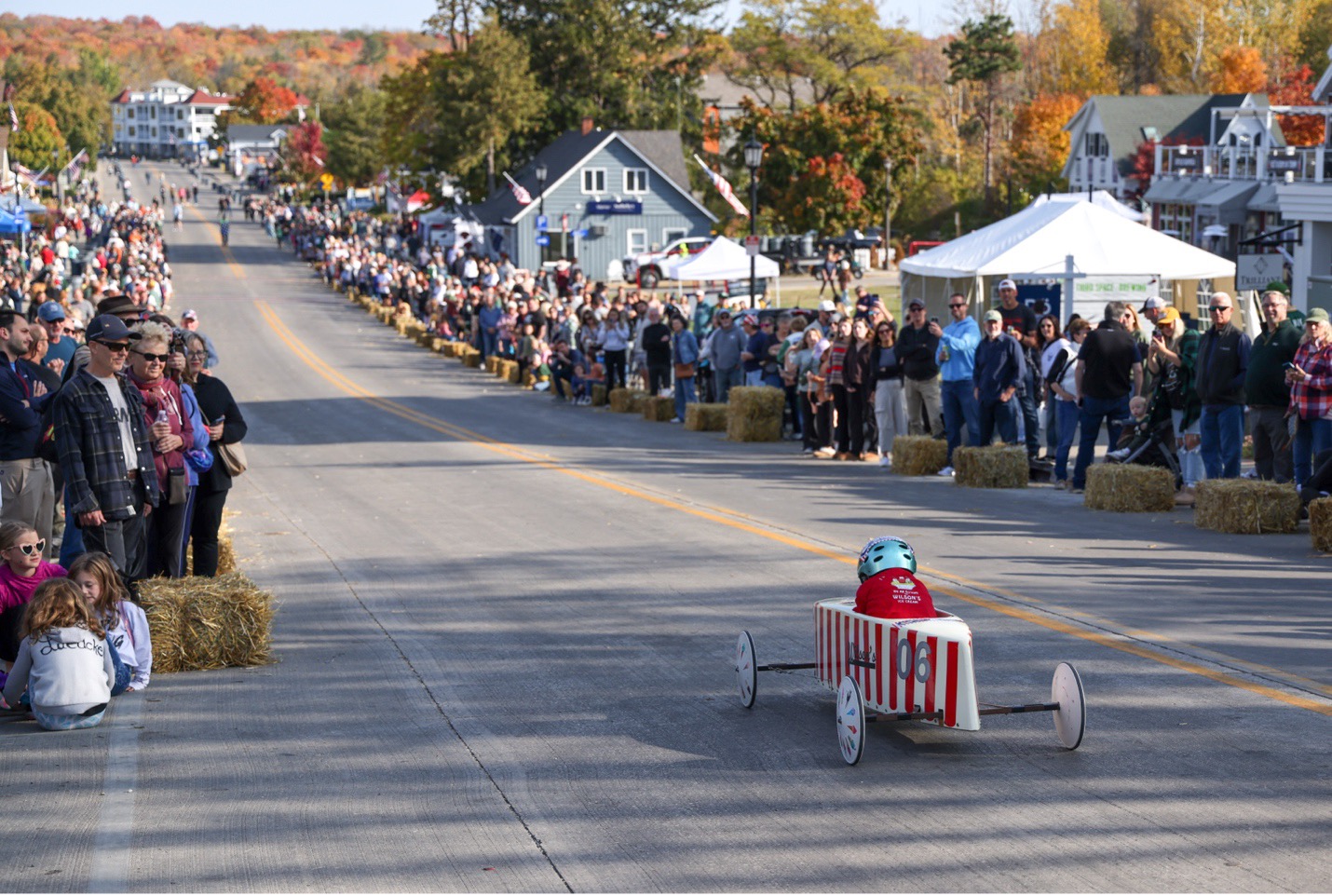 Kid in red and white derby car going down hill at Derby Race with spectators on both sides